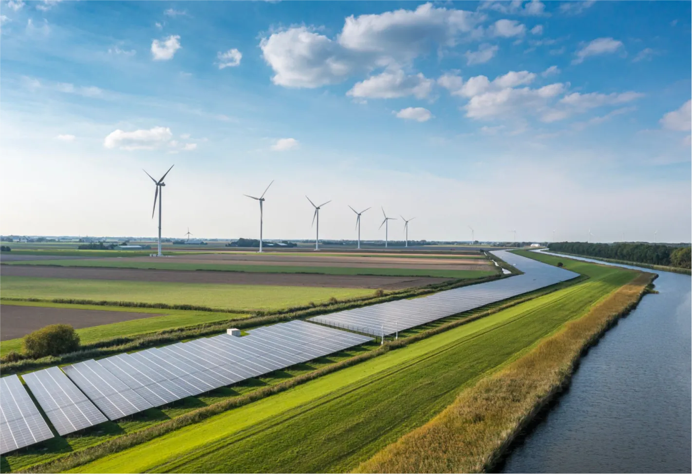 Wind turbines and solar panels along river in renewable energy farm