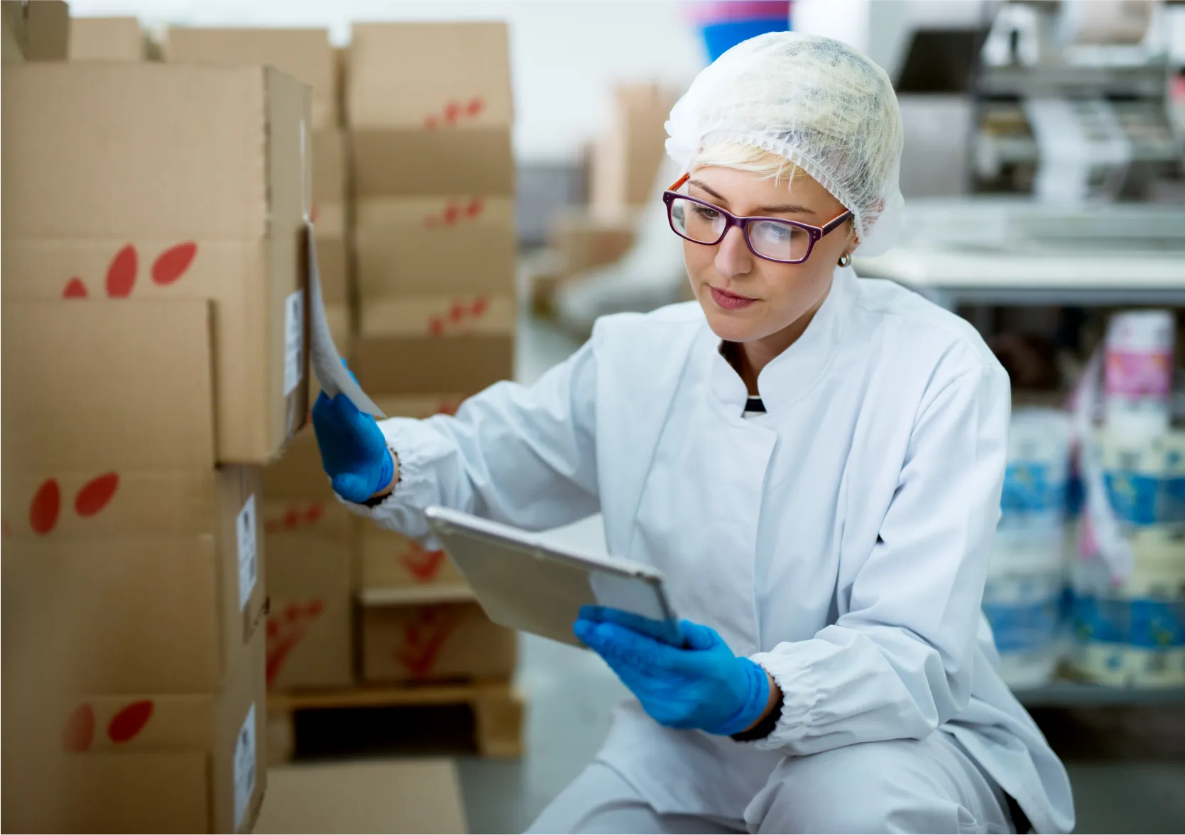 Female quality control worker in food packaging facility checking inventory on tablet