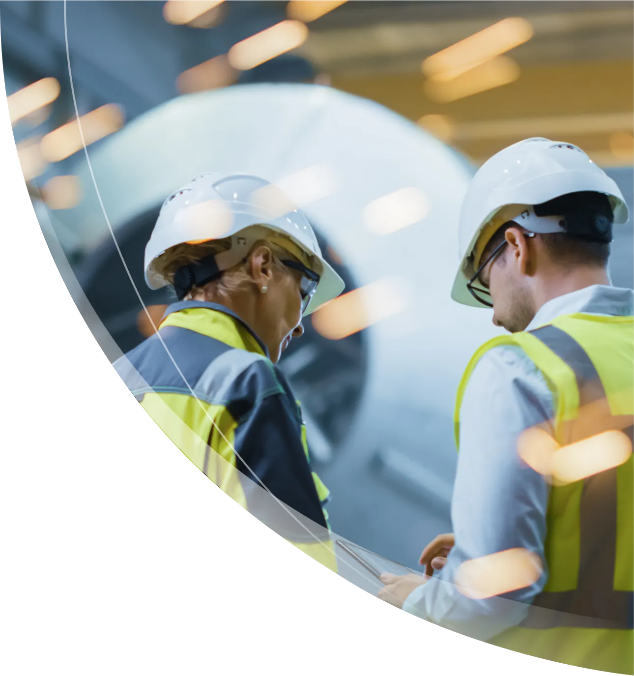 Industrial engineers with safety helmets and reflective vests discussing operations in a manufacturing facility