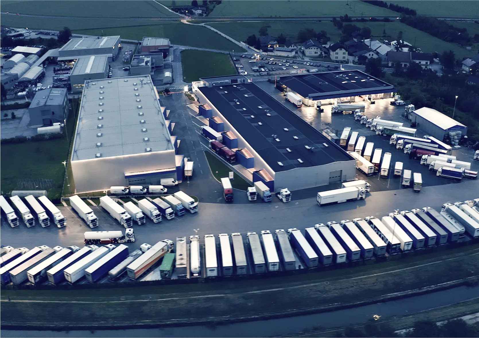 Aerial view of industrial logistics center with refrigerated trucks and warehouses at dusk